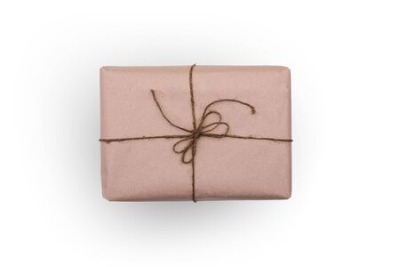 The box is wrapped in brown paper and tied with thread. Rectangular packaging isolated on a white background. Concept of mail delivery or event giftの写真素材