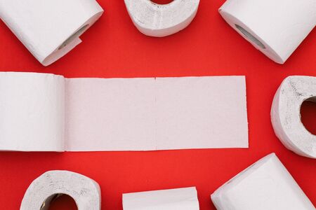 Toilet paper on a red background. Unfolded roll of white paper with empty place for text. Top view, copy spaceの写真素材