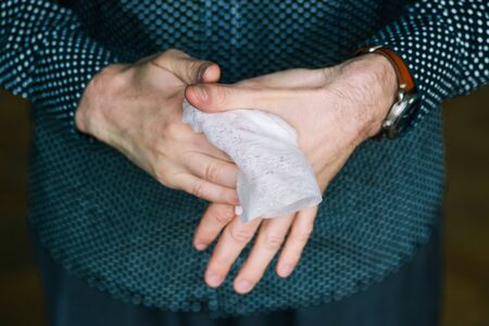 Man cleans his hands with a white soft cloth. Disinfection against viruses and bacteria at home or in the officeの写真素材