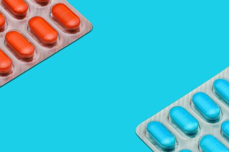 Pills in blue and orange on a colored background with copy space. Medicine and healthcare concept.