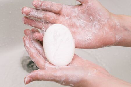 Hands rubbed with soap. Hand washing to prevent the coronavirus pandemic. A piece of soap in the palms close-up.の写真素材