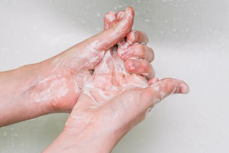 Woman uses soap and washes her hands under a faucet. Hygiene and hand cleaning. Prevention and control of coronavirus.の写真素材