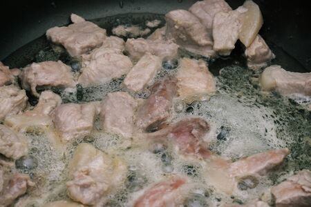 Pieces of raw meat with vegetable oil are fried in a pan. The process of cooking. The meat is cooked in a pan close-upの写真素材