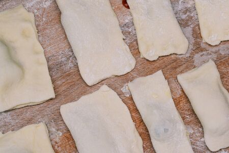 Sliced dough into rectangles. Slices of dough on a cutting wooden board. Making sweet homemade...