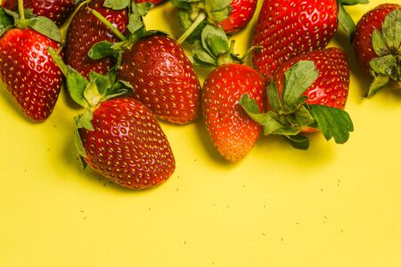 A closeup of fresh strawberries. Top view of fresh and juicy strawberries on a yellow backgroundの写真素材