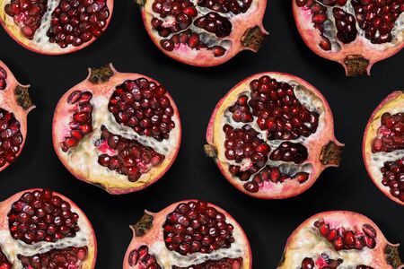 Pattern of ripe pomegranates on a black background. Slices of pomegranate with grains. A top view of a flat layout.の写真素材