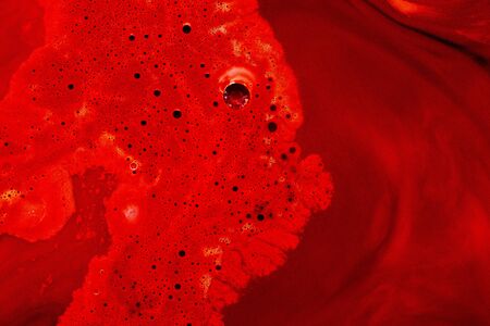 Spilled red paint with blisters and streaks. Close-up of the red spot. Abstract natural backgroundの写真素材
