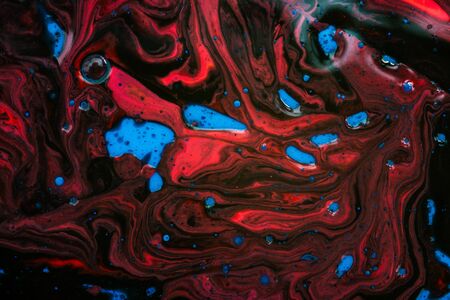 Abstract background with waves and streaks of blue, black and red colors. Natural background of oil and watercolor paints with water addition.の写真素材