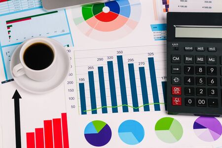 Workplace with a calculator and diagrams on the table close-up. A top view of a flat layout. Work from home, freelance. Business concept and accountingの写真素材