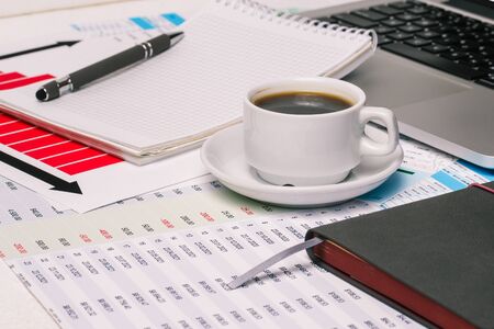 Office Desk workspace with coffee Cup, diary, Notepad and computer. Documents and tables with numbers. Business concept.の写真素材