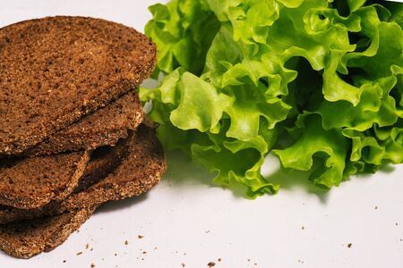 Fresh green lettuce leaves and rye bread on a white background. Healthy and vegetarian food. Food delivery.の写真素材