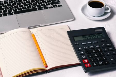Calculator, a diary, an open laptop, a Cup of coffee, and a notebook on the desktop. Accounting, Finance and business.の写真素材