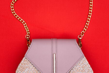 Womens bag with a gold chain on a red background. Womens set of fashion accessories. Top view, copy of the space.の写真素材