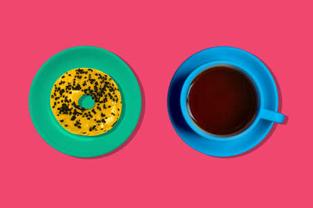 Yellow doughnut and a blue coffee Cup on a colored background. Creative minimal style.の写真素材