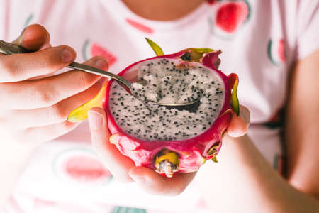 Woman is the tropical fruit of pitaya. Exotic fruits for a healthy diet. Red dragon fruit. Vegetarian food.の写真素材