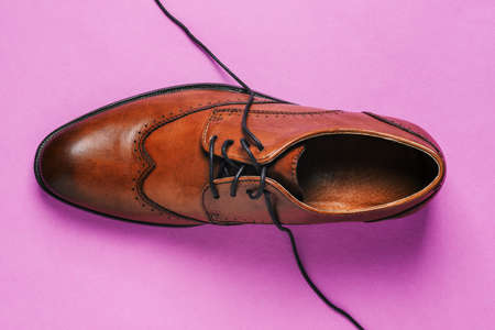 Brown shoes on a colored background with untied laces. Fashionable classic leather shoes. Mens style. The view from the topの写真素材