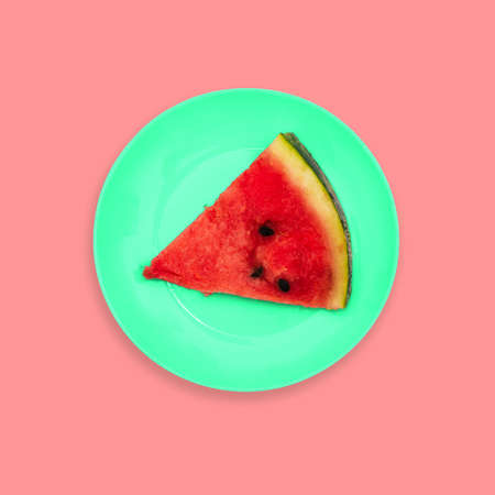 A slice of watermelon on a plate. Creative color background. Minimal style. A top view of a flat layout.の写真素材