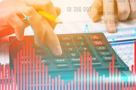 Businessman counts on a calculator. Earnings growth chart and figures. Company revenue forecast and data analysis. Business concept. Tinted photo.の写真素材