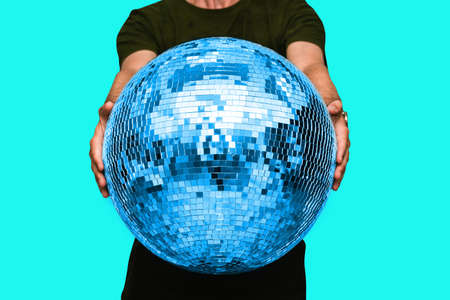 Man holds a disco ball in his hands. Concept of a party and disco in a night club. Minimal attractive styleの写真素材