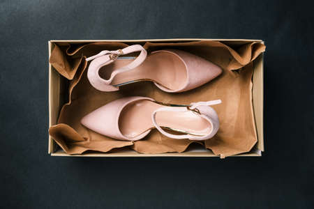 Beige shoes in a rectangular box on a black background. New womens shoes with a clasp in the package. Womens fashion. A top view of a flat layout.の写真素材