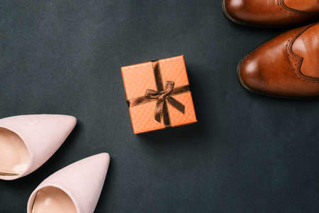 Womens and mens shoes and a gift box with a ribbon on a black background. Fashionable and stylish accessories. Sale and delivery of shoesの写真素材