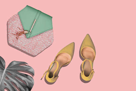 Stylish ladies bag, fashionable Golden shoes and a monstera leaf on a pink background. The concept of fashion in pastel colours. top view, flat layoutの写真素材