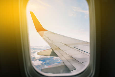 Airplane wing and sky from the airplane window. View through the airplane window. Flight on a...