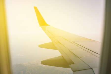 View of the wing of the plane from the window to the mountains. Flight on a passenger plane on vacationの写真素材