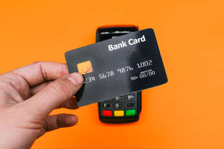 Payment for purchases by credit card. Black plastic card and cash register. The customer pays by credit card for a product or service in a store. Modern payment terminal. Commercial and businessの写真素材