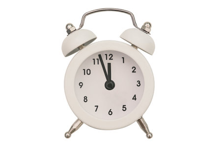 Alarm clock close-up isolated on a white background. White round clock. The hands of an old alarm clock with a bell show the time at twelve oclock.の写真素材