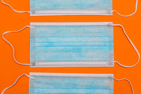 Medical masks on an orange background. Blue surgical mask to protect against the covid-19 epidemic....