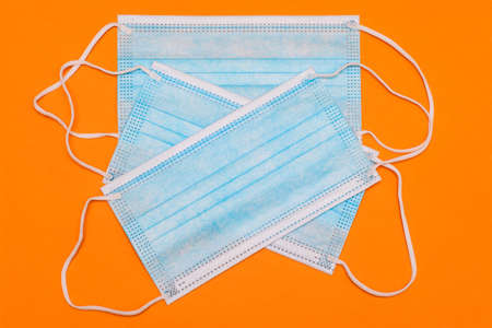 Blue disposable medical mask on a colored background. Surgical three-layer mask against viruses and diseases. Health and medicine. Protection, health care consumablesの写真素材