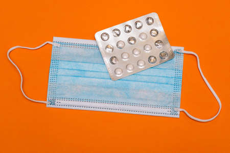 Medical mask and open pack of pills. Treating diseases and protecting against pollution, bacteria and viruses. Vaccine Coronavirus. Pharmaceuticals and Medicineの写真素材