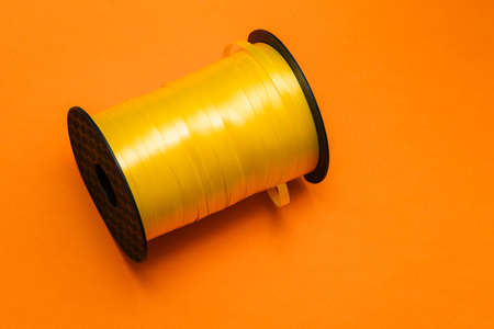 Ribbon reel close-up. Yellow decorative tape for balloons and gift wrapping. Birthday, Party and...