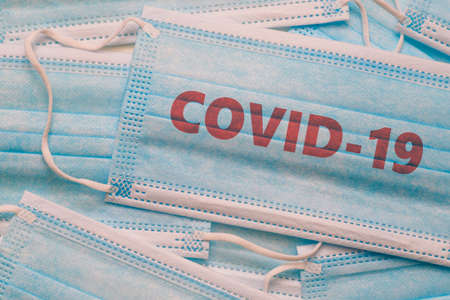 Background from medical masks and the inscription COVID-19. Human safety during a pandemic.の写真素材