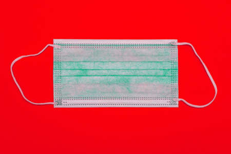 Medical face mask on a red background. Respiratory protection. Safety during a pandemic.の写真素材