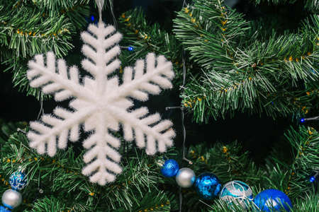 Christmas tree and big white snowflake. Green spruce branches are decorated with toys and balls.の写真素材