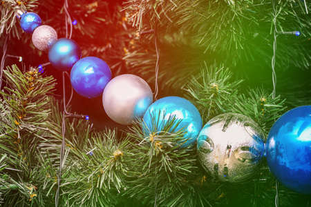 Large Christmas balls on the tree. Spruce green branches with toys. Glowing garlands close-up. Christmas background. New year conceptの写真素材