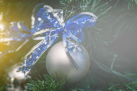Christmas ball on the tree close-up. A silver Christmas toy with a blue festive bow. New year conceptの写真素材