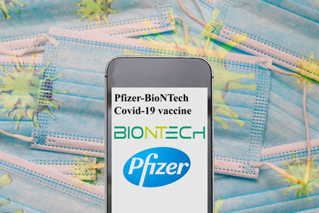 Pfizer biontech covid 19 vaccine. Reino unido vacina. UK approved pfizer vaccine. News on a smartphone. Disposable masks with coronavirus bacteria: NEW YORK, USA, November 30, 2020のeditorial素材