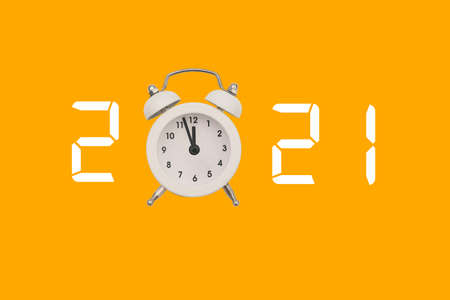 White alarm clock and numbers 2021 on a colored background. The hands of the clock are approaching...