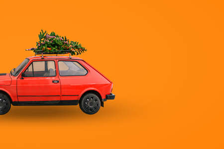 Red retro car. Christmas tree on the roof of the car. Delivery of goods, New Years trips and tours. Christmas backgroundの写真素材