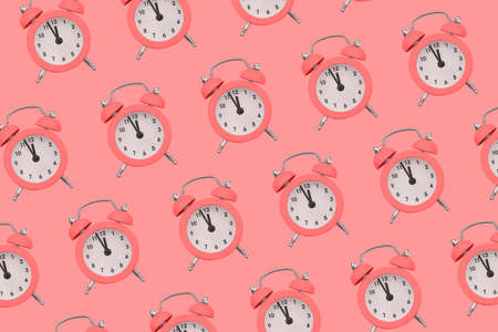 Pink alarm clock on a colored background. Fashionable pattern with watches. The concept of time, alert. Minimal styleの写真素材
