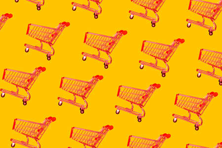 Empty red shopping basket in a store on a yellow background. Minimal style, pattern. Sale, discounts, shopaholism conceptの写真素材