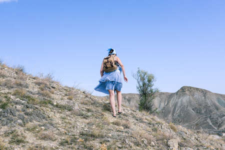 Traveler with a backpack walks through the mountainous area on a sunny day. Active lifestyle. Sports and tourismの写真素材