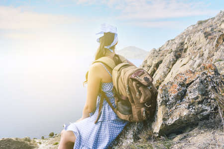 Young girl on vacation. Hiker with a backpack is resting on the top of the mountain and enjoying the...