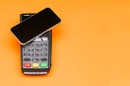 Payment terminal and smartphone with copy space. Contactless payment for goods. E-commerce and business. Contactless payment for purchasesの写真素材