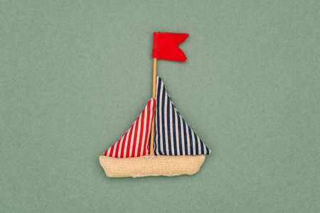 Boat made of fabric on a green background. Handmade soft toy. Childrens handicraft for the development of hand motor skills. Travel and tourism, summer vacationsの写真素材