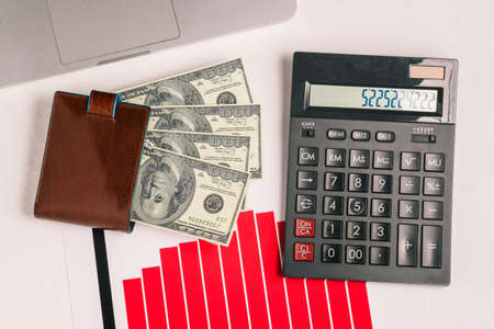 Computer, calculator, growth charts and dollar bills in a wallet. Cash, investment and profit of the company. The concept of success and making money. Top view, flat layの写真素材