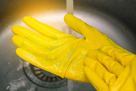 Human hands in yellow rubber gloves. Window washing, house cleaning. Rubber protective glovesの写真素材